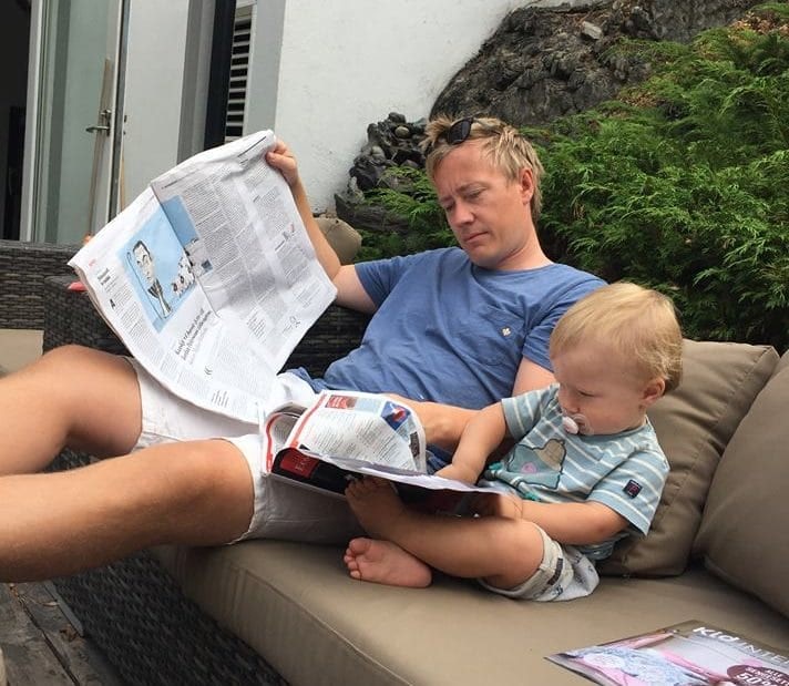 Lege hjem til far og barn som leser avisen på verandaen