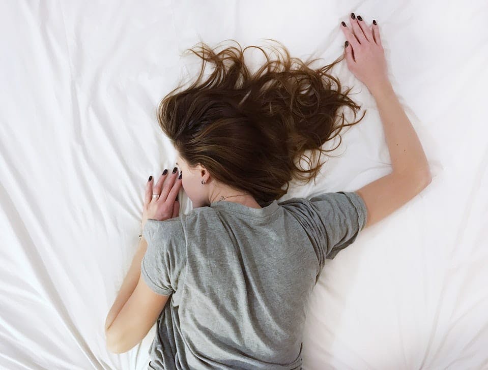 kvinne med depresjon og angst ligger i sengen på magen